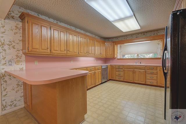 kitchen with kitchen peninsula, black refrigerator, stainless steel dishwasher, and sink