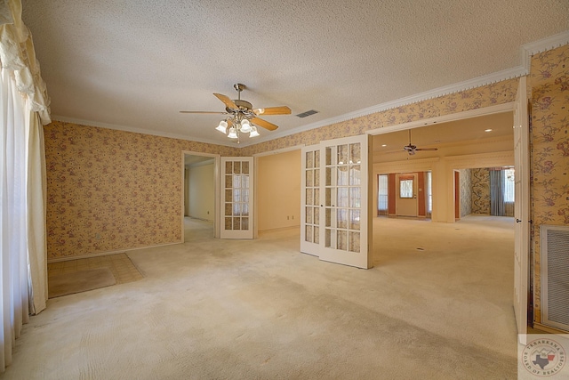 empty room with crown molding, light carpet, ceiling fan, french doors, and a textured ceiling