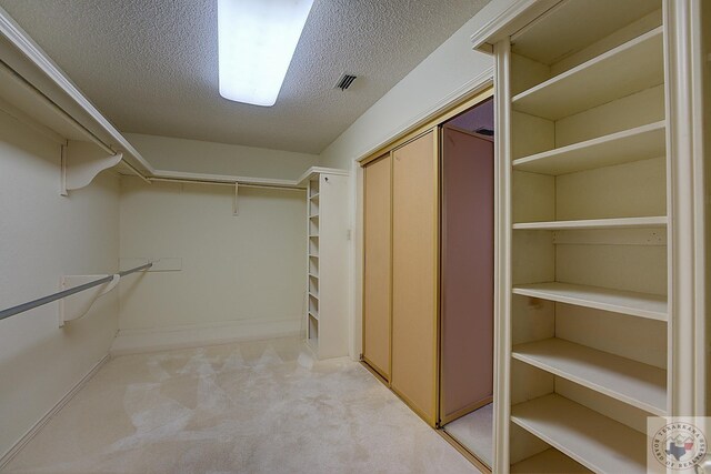 walk in closet featuring light carpet