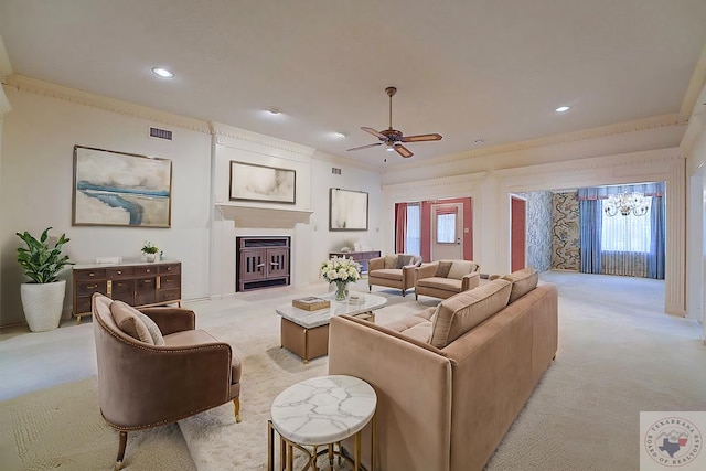 carpeted living room featuring ceiling fan with notable chandelier and ornamental molding