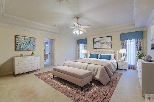 bedroom with ensuite bathroom, crown molding, a raised ceiling, light colored carpet, and ceiling fan