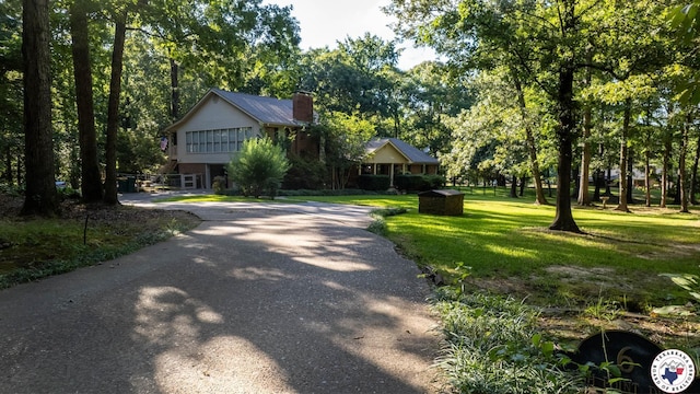 6 High Point Dr, Texarkana, TX 75503 - view of front of house with a front lawn, a chimney, driveway, and view of wooded area