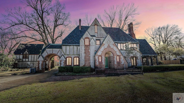 tudor-style house with a lawn and central air condition unit