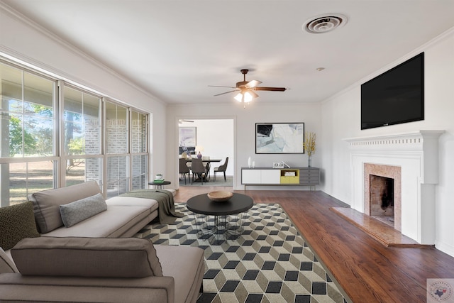 living room with a premium fireplace, ceiling fan, ornamental molding, and dark hardwood / wood-style flooring