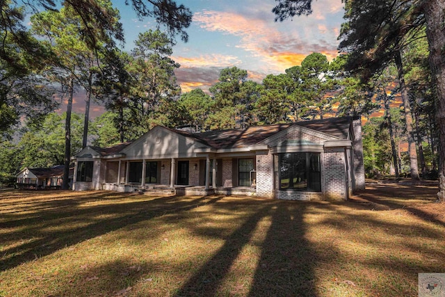 back house at dusk featuring a lawn