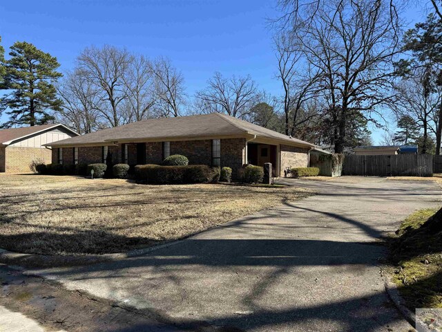 view of front facade with brick siding, driveway, and fence