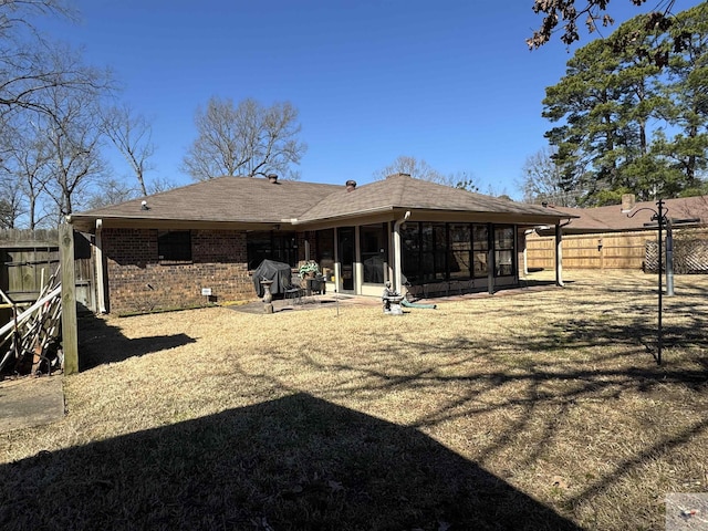 rear view of property featuring a patio, a fenced backyard, brick siding, a shingled roof, and a sunroom