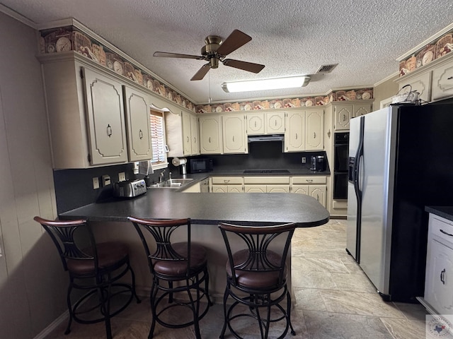 kitchen with a peninsula, exhaust hood, visible vents, black appliances, and dark countertops