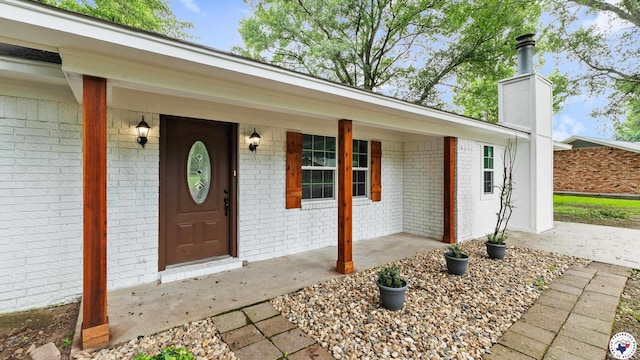 10 Vernon St, Hooks, TX 75561 - entrance to property featuring brick siding, a chimney, and a porch