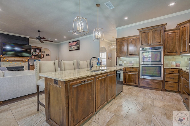 kitchen featuring appliances with stainless steel finishes, an island with sink, sink, hanging light fixtures, and a breakfast bar area