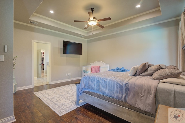 bedroom with ceiling fan, crown molding, dark wood-type flooring, and a tray ceiling