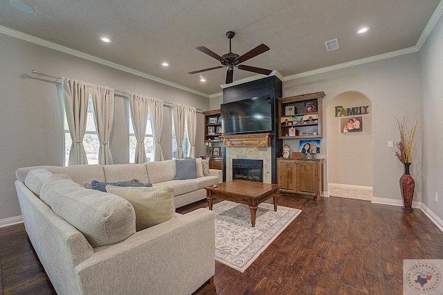 living room featuring a fireplace, dark wood-type flooring, ceiling fan, and ornamental molding