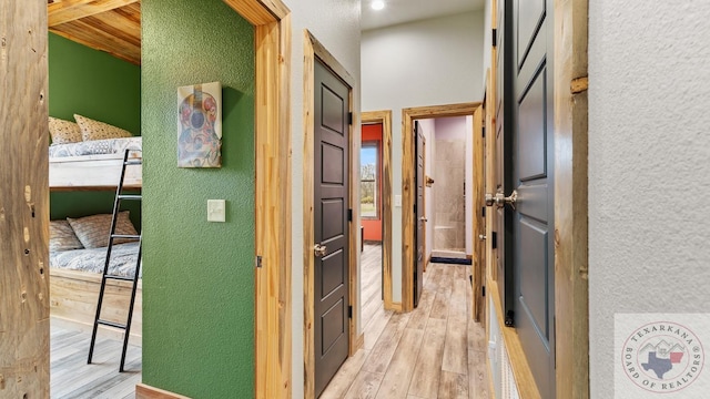 hall with light wood-type flooring and a textured wall