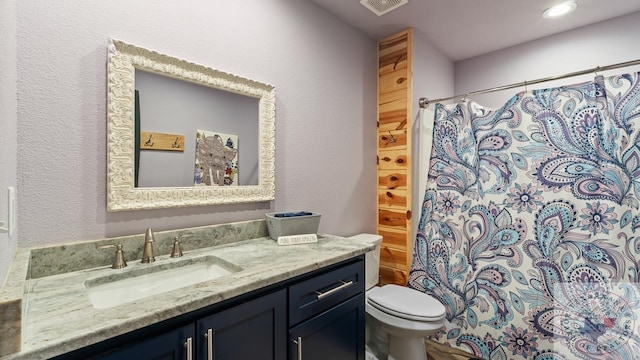 bathroom featuring visible vents, a textured wall, toilet, curtained shower, and vanity