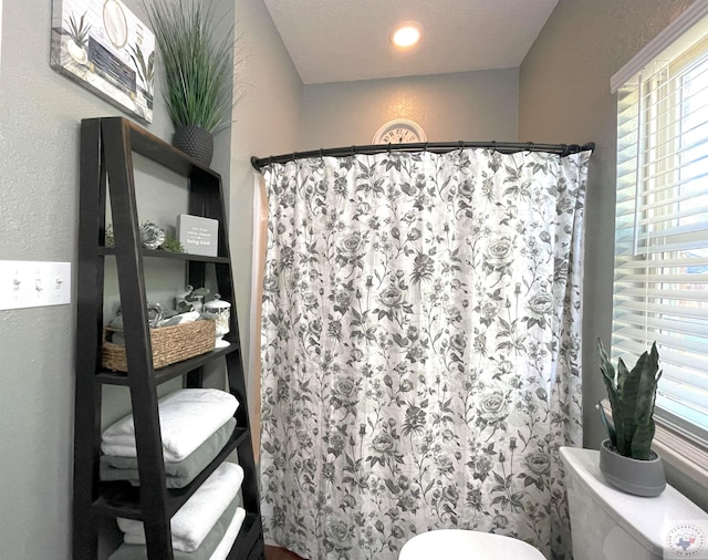 bathroom featuring toilet, walk in shower, and a textured ceiling