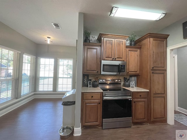 kitchen featuring dark hardwood / wood-style flooring, stainless steel appliances, and tasteful backsplash