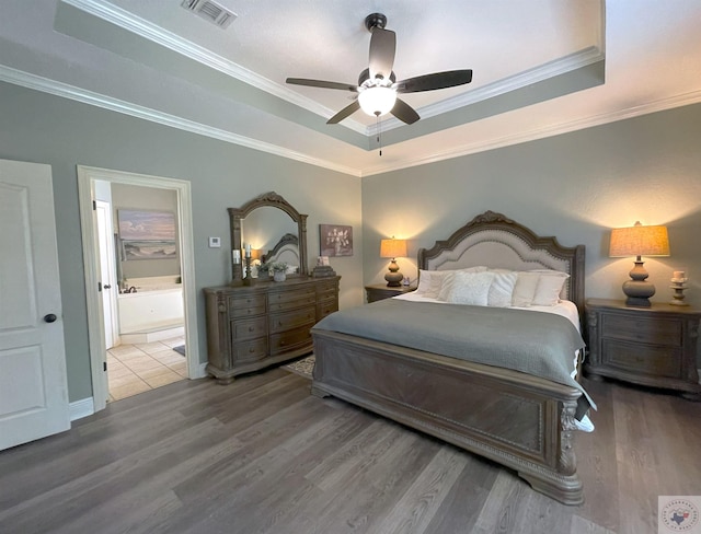 bedroom featuring ceiling fan, hardwood / wood-style flooring, connected bathroom, and a tray ceiling