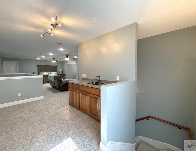 kitchen featuring ceiling fan, sink, a textured ceiling, and light carpet