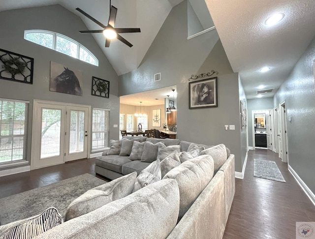 living room featuring plenty of natural light, ceiling fan with notable chandelier, dark hardwood / wood-style floors, and high vaulted ceiling