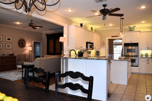 2905 Landon Ln, Texarkana, TX 75503 - kitchen featuring a ceiling fan, stainless steel appliances, dark stone countertops, a peninsula, and white cabinets