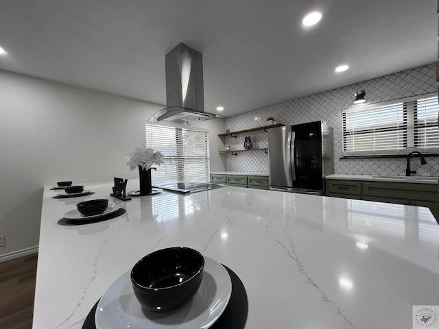 kitchen with sink, stainless steel refrigerator, light stone countertops, and island exhaust hood