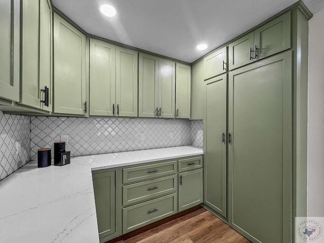 kitchen featuring green cabinetry, dark hardwood / wood-style floors, tasteful backsplash, and light stone counters