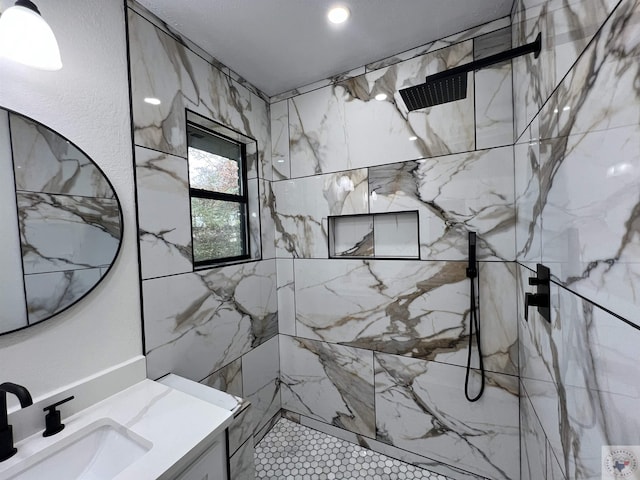 bathroom featuring tiled shower and vanity