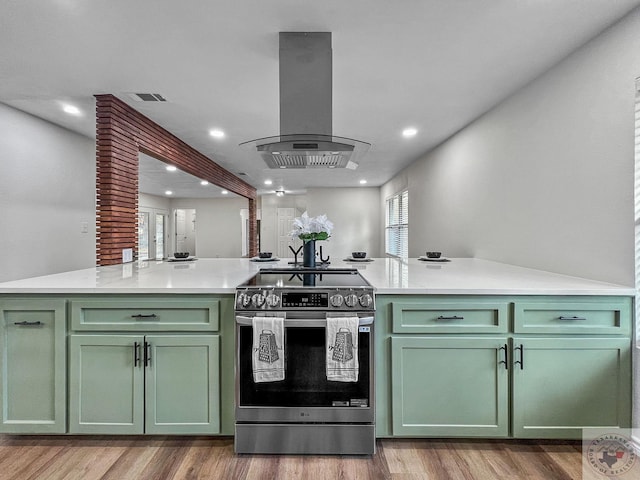 kitchen featuring island exhaust hood, green cabinets, stainless steel range with electric stovetop, kitchen peninsula, and light hardwood / wood-style flooring