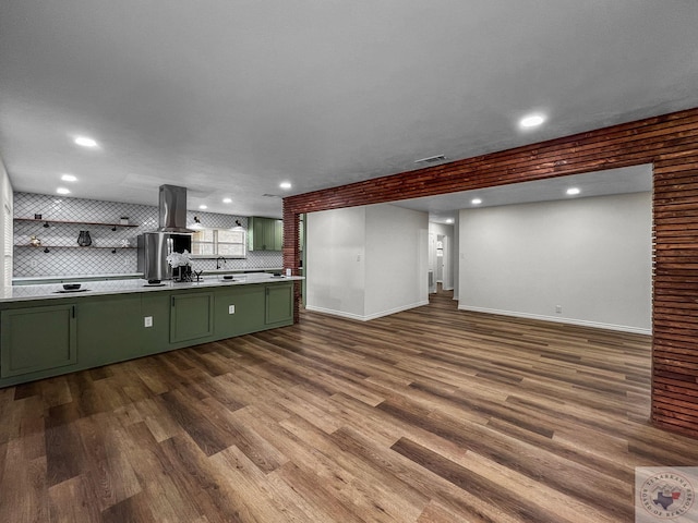 kitchen featuring wood-type flooring, island exhaust hood, decorative backsplash, sink, and green cabinets