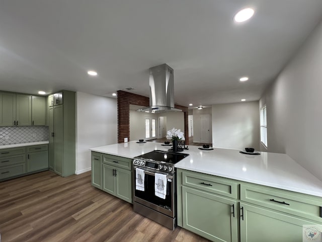 kitchen with stainless steel electric range, island exhaust hood, green cabinetry, and decorative backsplash