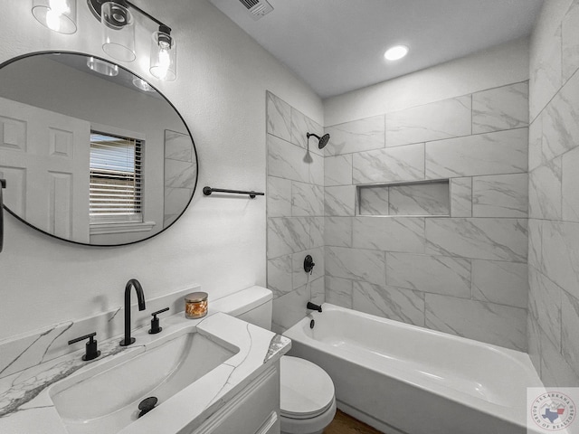 full bathroom featuring toilet, vanity, and tiled shower / bath