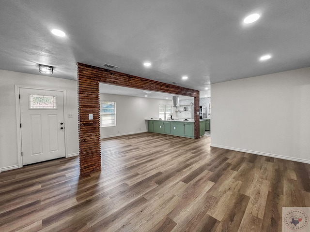 unfurnished living room with decorative columns and dark wood-type flooring