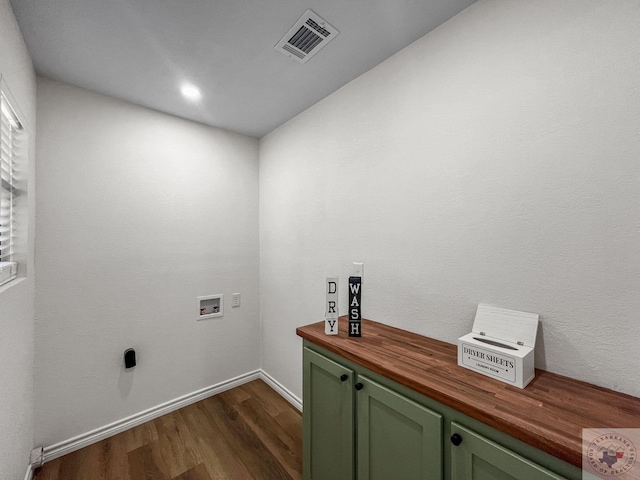 washroom with washer hookup, dark wood-type flooring, and cabinets