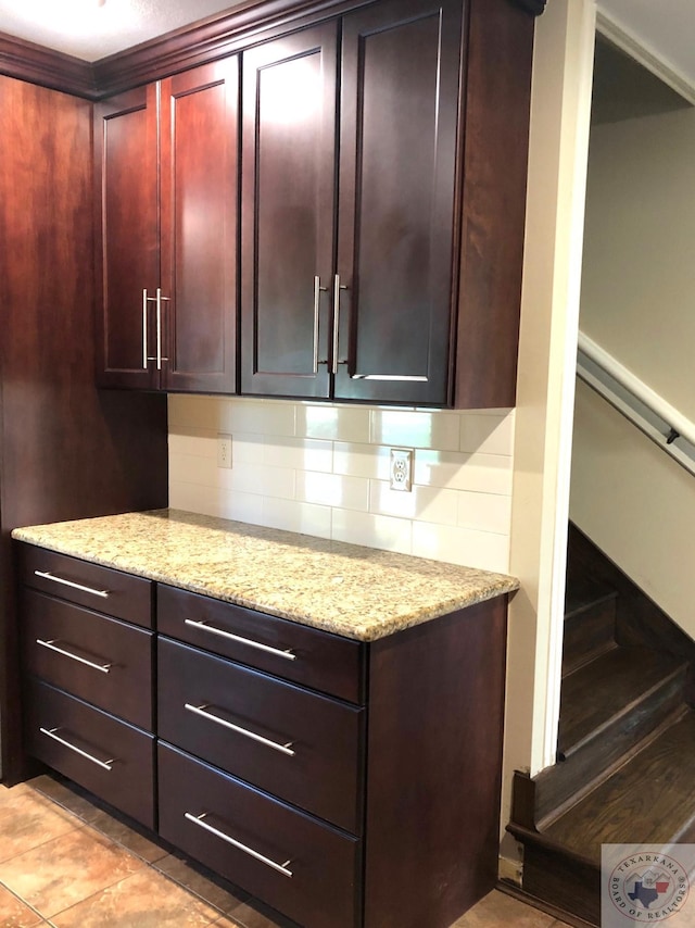 kitchen featuring tasteful backsplash, light tile patterned floors, and light stone counters