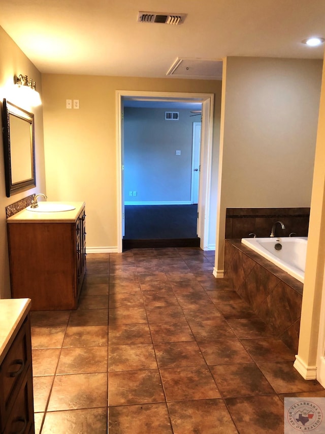 bathroom featuring a relaxing tiled tub, tile patterned floors, and vanity