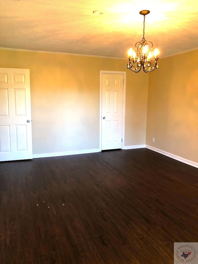 spare room featuring a notable chandelier, crown molding, and dark hardwood / wood-style flooring