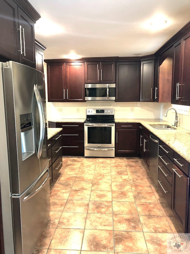 kitchen featuring sink, light tile patterned flooring, dark brown cabinetry, and appliances with stainless steel finishes