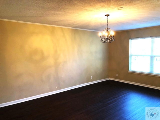 empty room featuring a textured ceiling, dark hardwood / wood-style floors, a notable chandelier, and ornamental molding