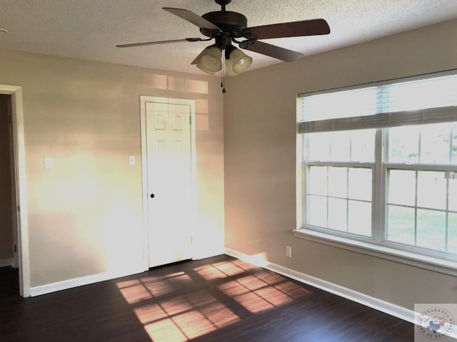 unfurnished bedroom featuring ceiling fan, multiple windows, dark hardwood / wood-style floors, and a textured ceiling