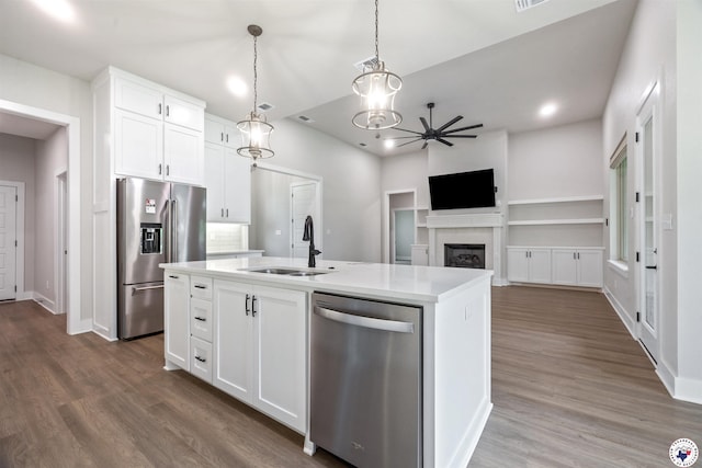 8409 Mandarin Cv, Texarkana, TX 75503 - kitchen featuring stainless steel appliances, a sink, a fireplace, dark wood-style floors, and light countertops