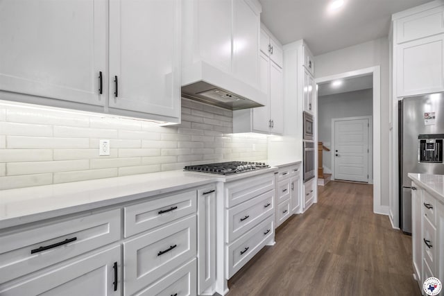 8409 Mandarin Cv, Texarkana, TX 75503 - kitchen featuring appliances with stainless steel finishes, white cabinets, dark wood-style floors, decorative backsplash, and light stone countertops