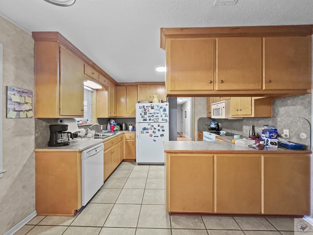 kitchen with a peninsula, white appliances, light tile patterned flooring, and light countertops