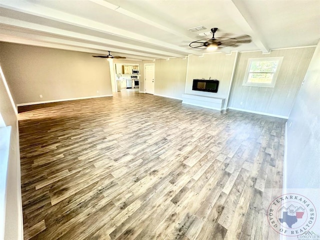 unfurnished living room featuring ceiling fan, hardwood / wood-style flooring, and beam ceiling