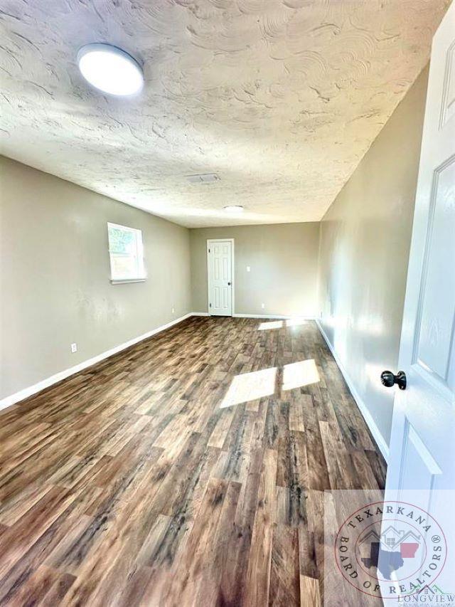 empty room featuring wood-type flooring and a textured ceiling