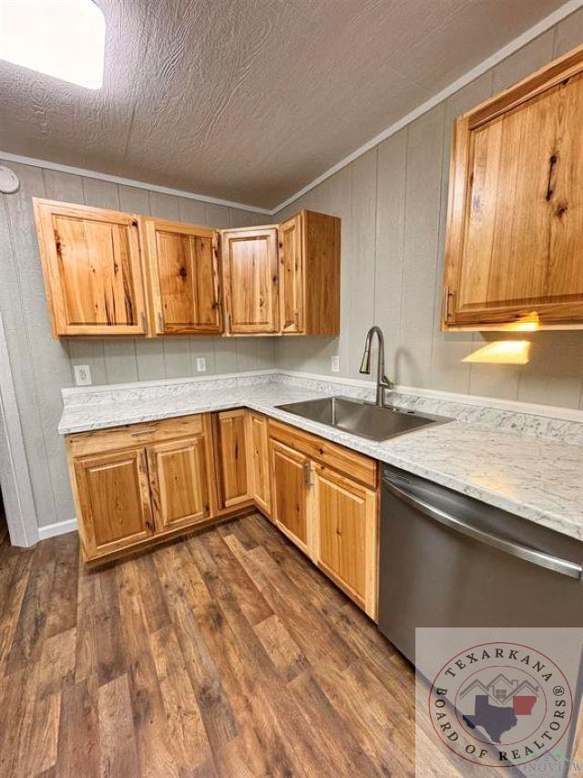 kitchen featuring light stone countertops, sink, dark hardwood / wood-style floors, stainless steel dishwasher, and crown molding