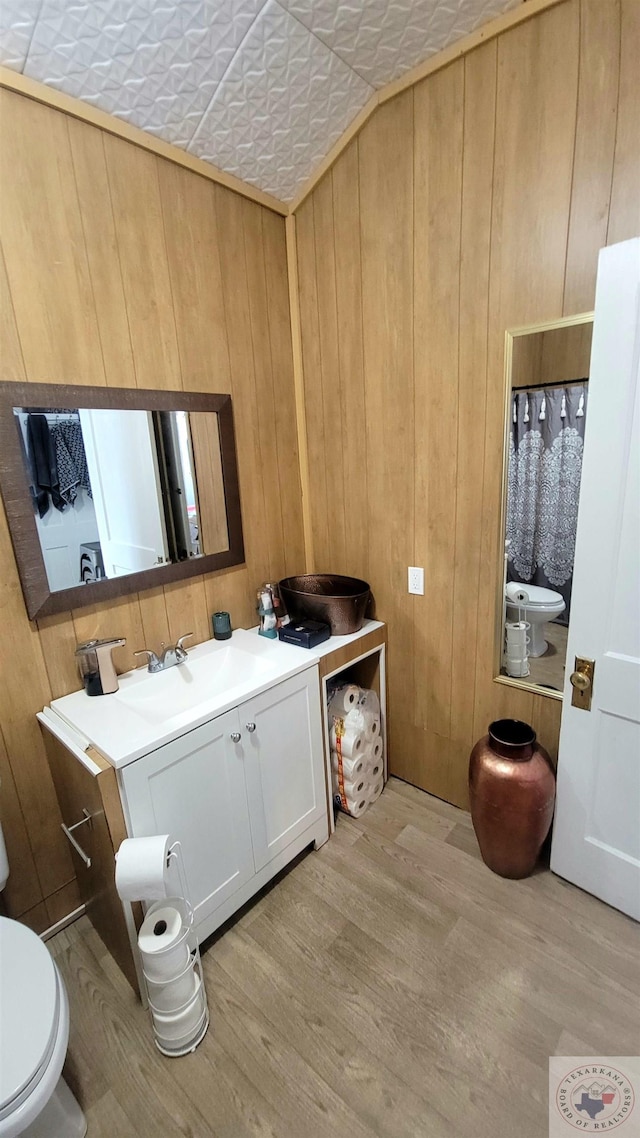 bathroom featuring wood-type flooring, wooden walls, and toilet