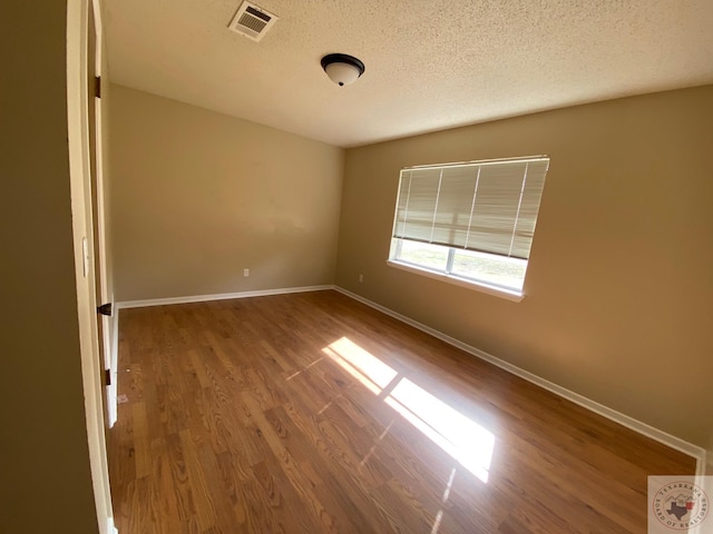 unfurnished room with a textured ceiling and wood-type flooring