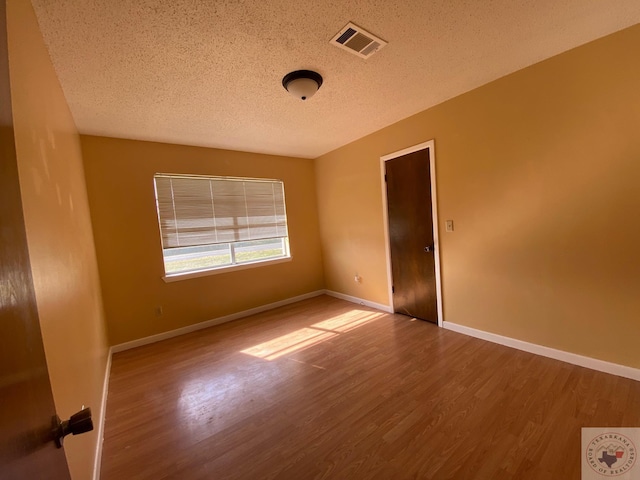 spare room featuring a textured ceiling and wood-type flooring