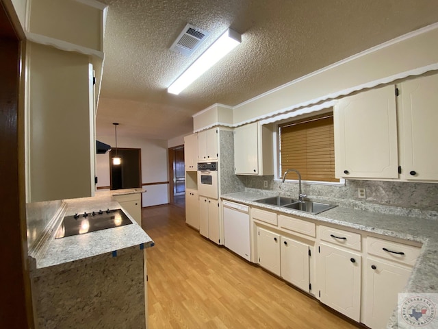 kitchen with white appliances, a textured ceiling, sink, white cabinets, and pendant lighting