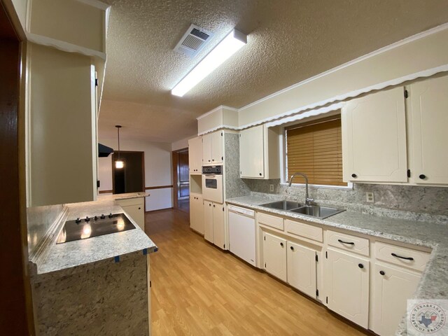 507 E Fannin St, Dekalb, TX 75559 - kitchen with white appliances, a textured ceiling, sink, white cabinets, and pendant lighting